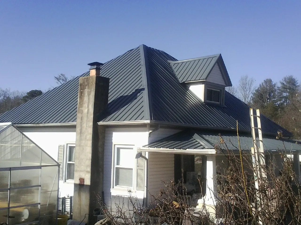 Dark blue standing seam metal roof on a white farmhouse with dormer — Slate & Tile Roof Repair by Roofing Brothers in Hacker Valley