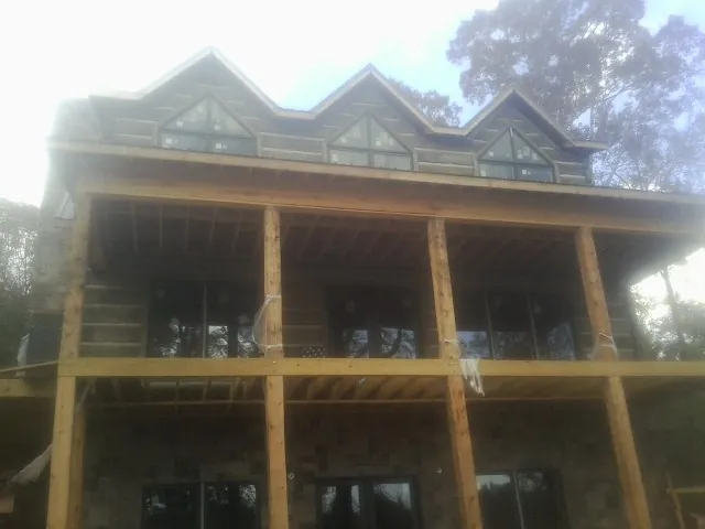 Dormers and porch framing on a large log home under construction — Roof Coating work by our crew in Hacker Valley