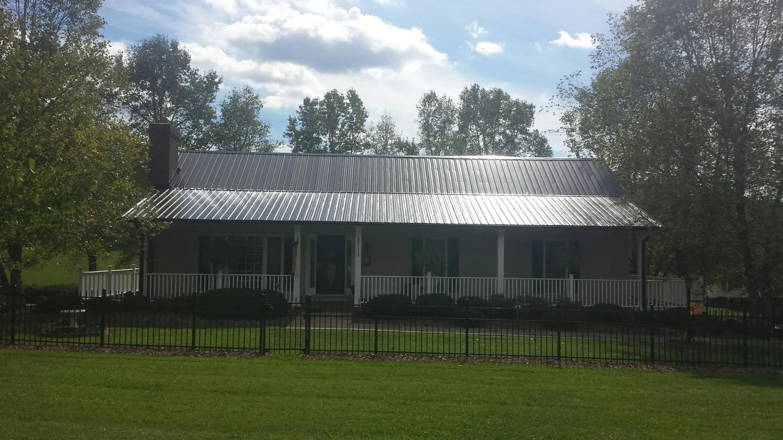 Gray metal roof on a brick ranch with a full width front porch — Gutter Guard Installation work by our crew in Hacker Valley