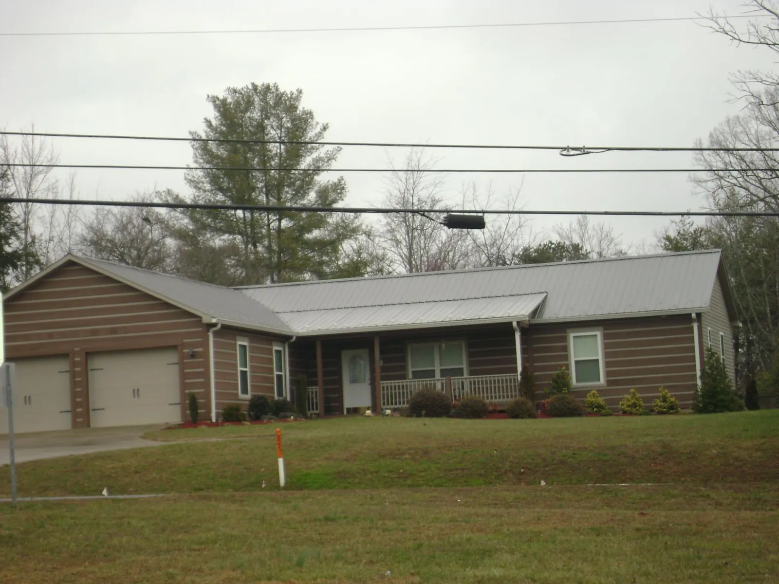 Gray metal roof on a log sided ranch home with a front porch in Hacker Valley