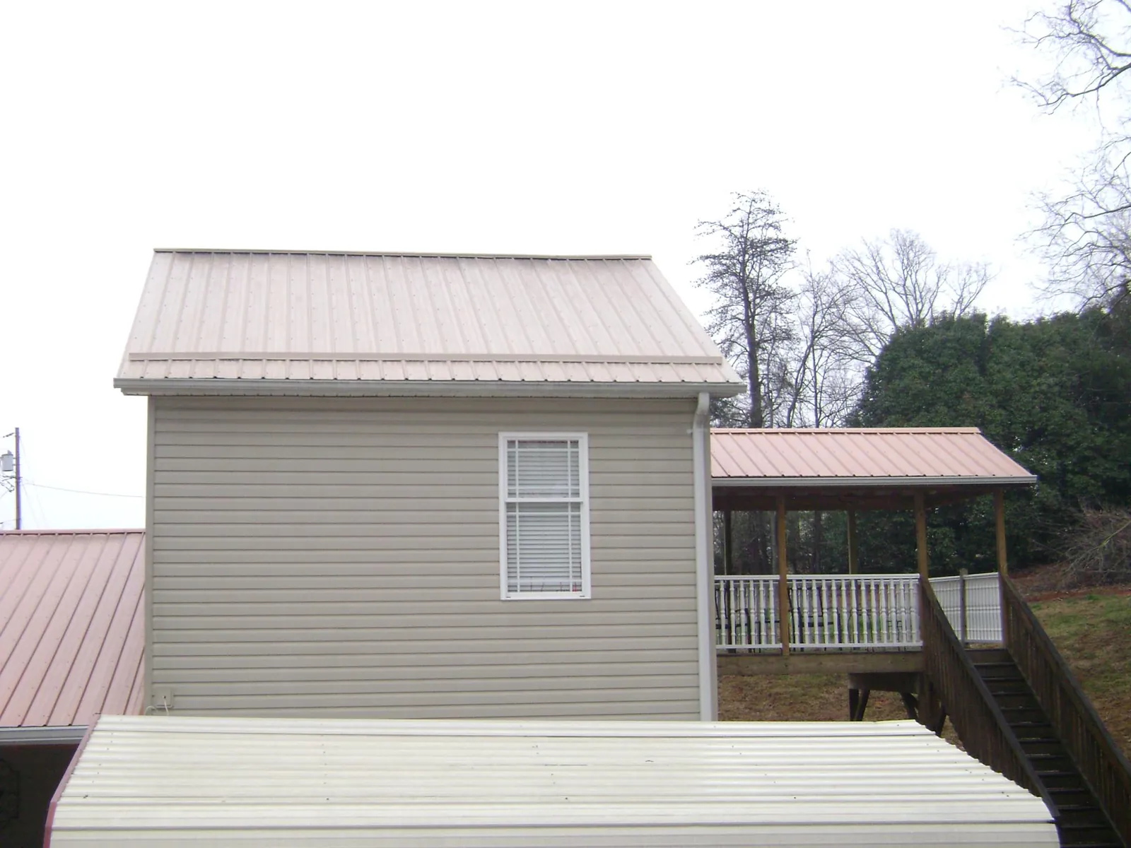 Tan metal roofs on a two story addition and attached porch, from a Roof Replacement job in Hacker Valley
