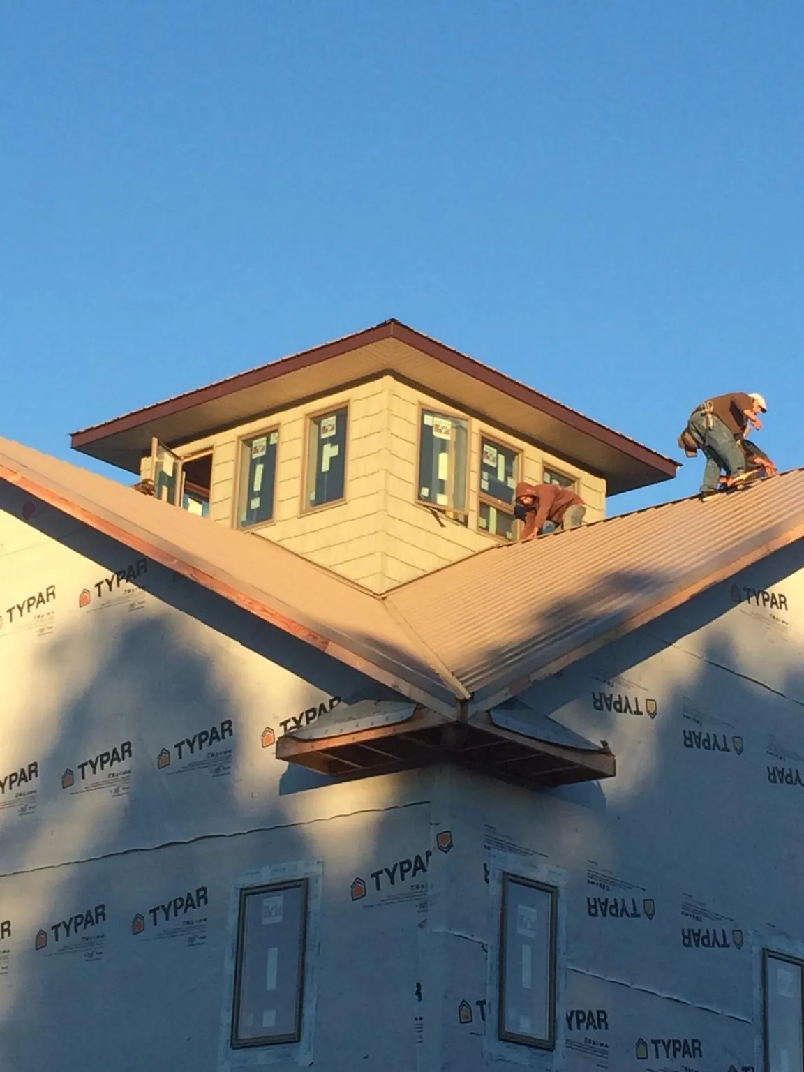 Roofers working around a rooftop cupola on a new metal roof at sunset — Roof Waterproofing in Hacker Valley by Roofing Brothers